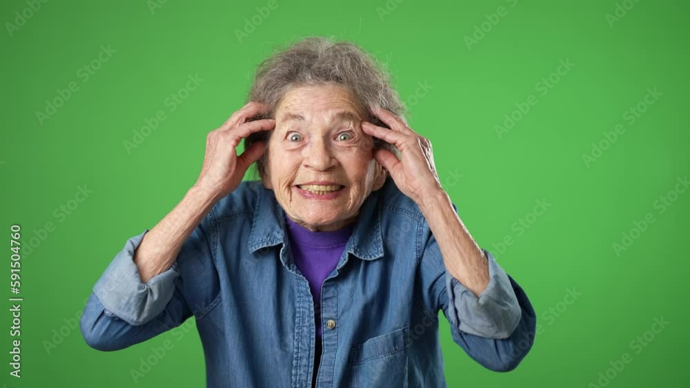Portrait of elderly senior old woman with wrinkled skin and grey hair looks at camera gives mind blown gesture showing explosion of ideas posing isolated on green screen background with copy space.