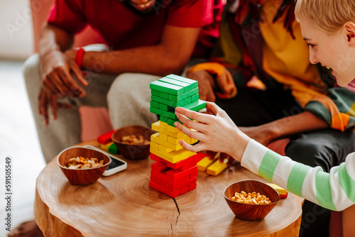 Happy friends playing block removal game on table at home