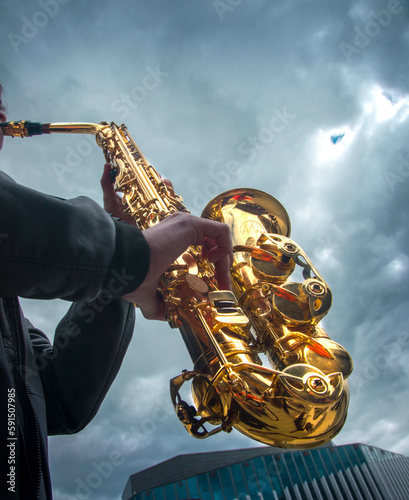 close-up of the hands of a street musician holding a gold-colored pump-action trumpet 