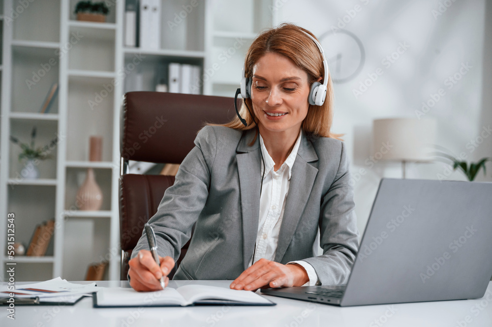 Writing information into document. Woman in business formal clothes is working in office Writing information into document. Woman in business formal clothes is working in office