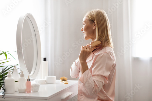 Valokuva Beautiful Middle Aged Woman Brushing Her Blonde Hair With Comb At Home