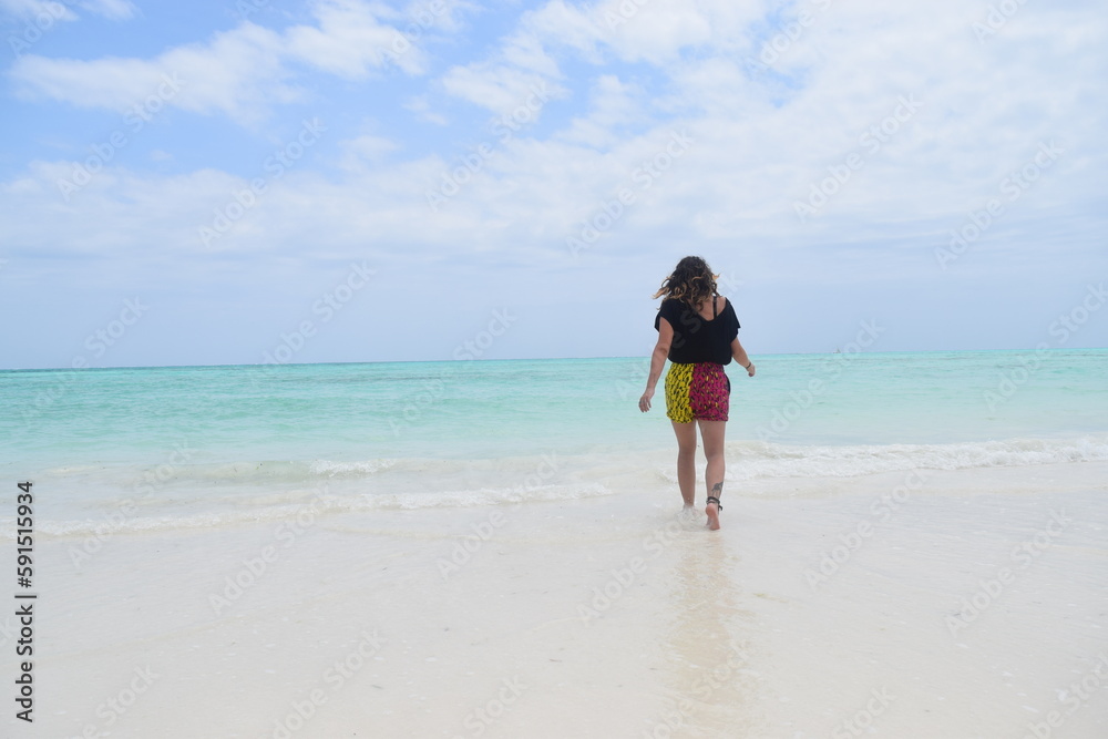 Young woman walks in the pristine waters of Zanzibar, Tanzania