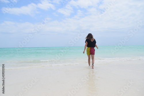 Young woman walks in the pristine waters of Zanzibar, Tanzania