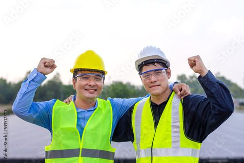 Two engineers stand with their necks crossed, congratulating the success of their work at a solar power plant.
