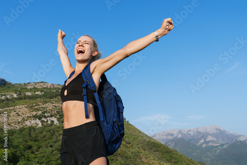 A young woman who is happy that she climbed the mountain. Hiking in summer