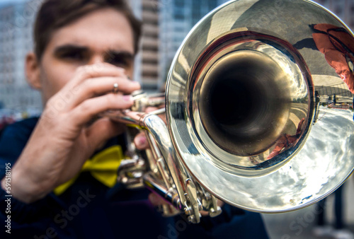 close-up of the hands of a street musician holding a gold-colored pump-action trumpet