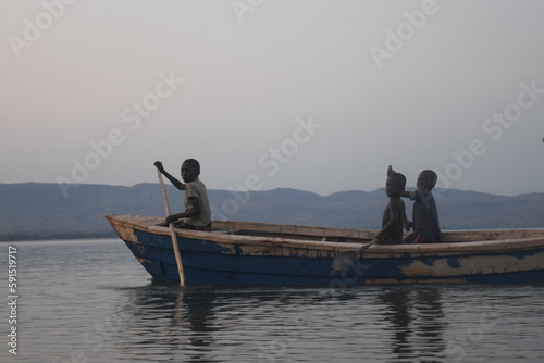 A family paddles by in a handmade fishing boat in a rural fishing village on Lake Malawi 