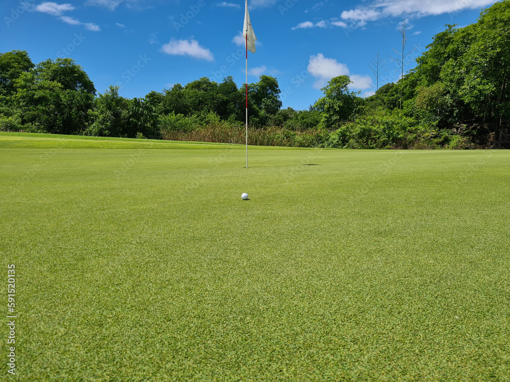 Obraz premium Golf ball in front of a flag on green