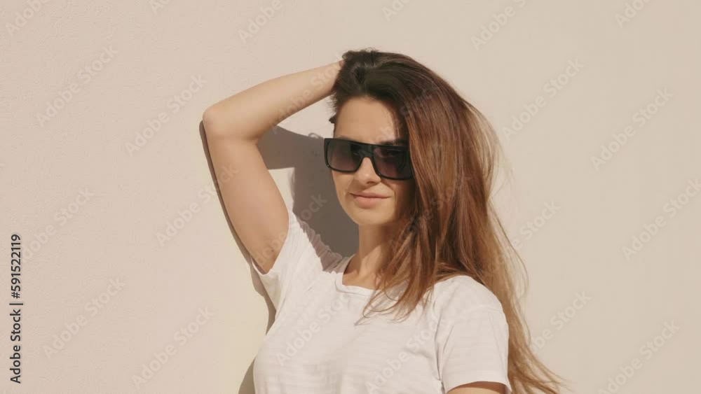 Female dressed in summer hipster clothes. She posing on the street background near wall. Funny and positive woman having fun in sunglasses