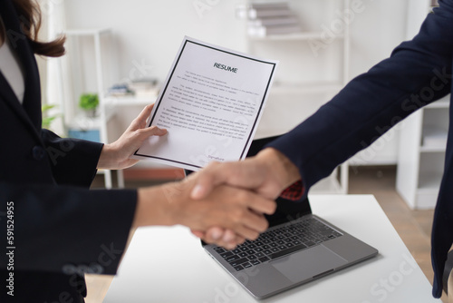 Young happy woman applying for job and giving she's CV to a manager during the interview and shakehand in the office. 