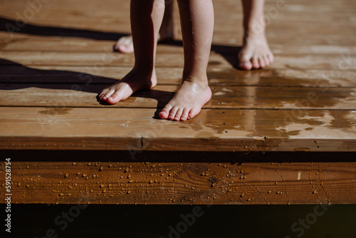 Low section of children feet on pier.