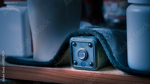 closeup hidden or spy camera under cloth on wooden shelf in dark room. Spy or detective or scandal concept.