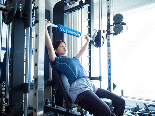 パワーラックでベンチプレスする女性