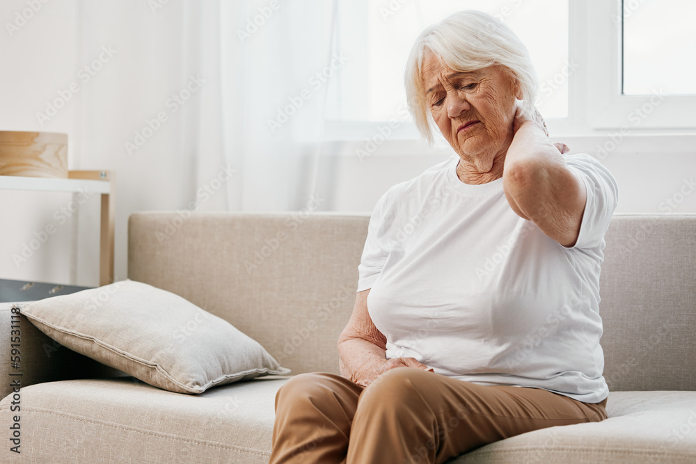 Elderly woman severe neck pain sitting on the sofa, health problems in