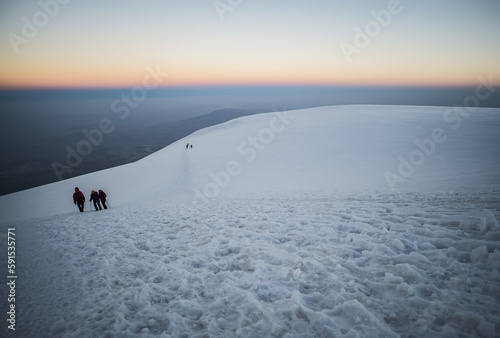 Climbers climbing Mount Ararat along the steep slope of the glacier in front of the summit, minimalist ascent of climbers
