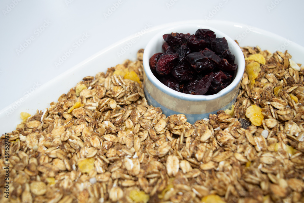 Plate of granola seeds with some cereals and a small portion of dry red berries in white background. Plate of granola seeds with some cereals and a small portion of dry red berries in white background.