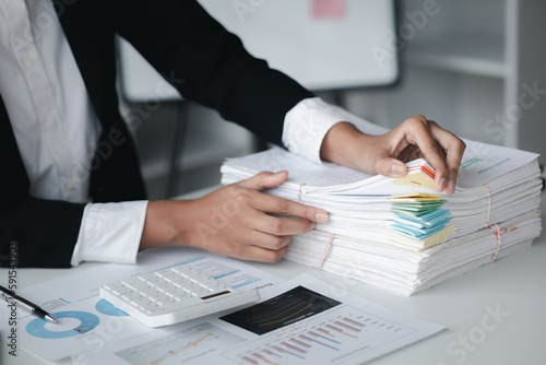 Businessman looking through stacks of papers on desk, corporate financial papers, monthly financial summary papers. Concept of document management in the organization.