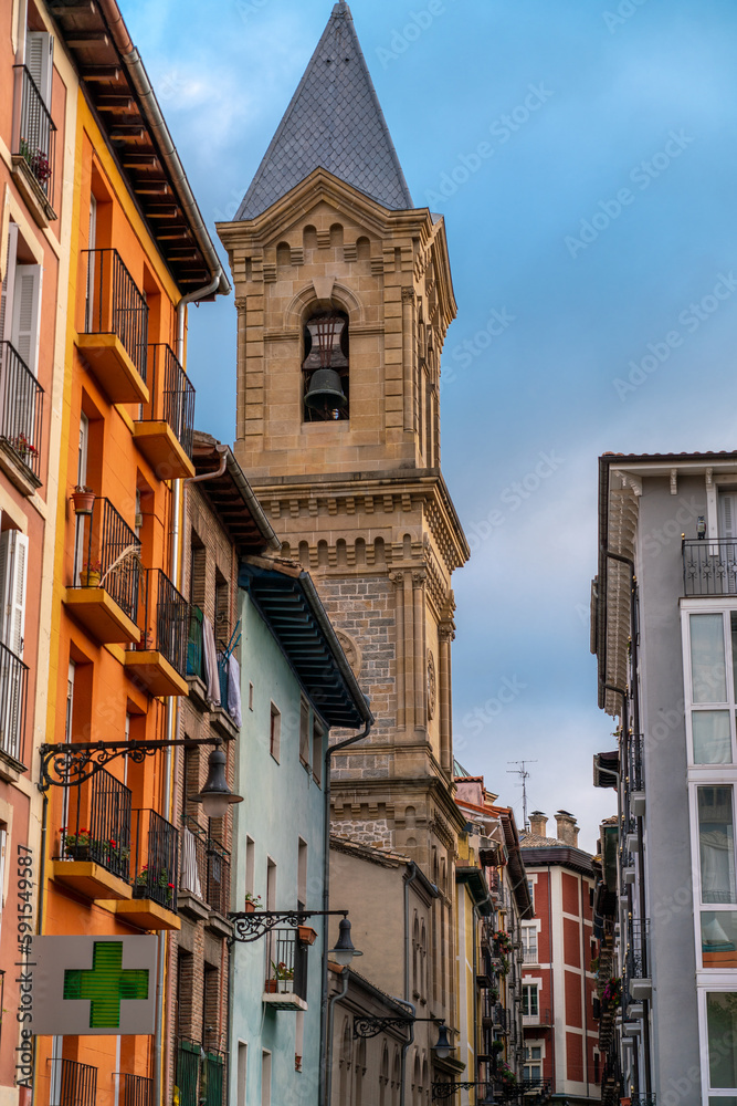 Pamplona, Navarra, SPAIN. The beautiful streets of the city of Pamplona. Beautifully coloured buildings with flowers of different colours, hanging from the balconies. Church tower in background. 