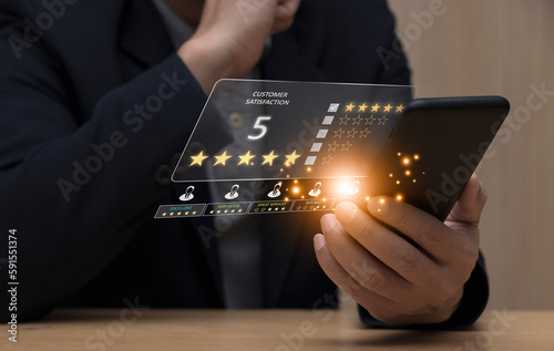 Businessman using smartphone to give feedback, service rating, satisfaction concept. Happy to sad emoticon scale response sign and poor service photo