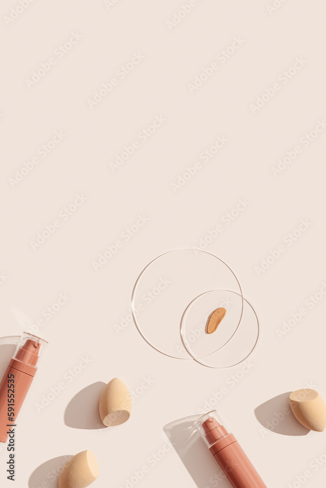 Bottle of makeup foundation cream, samples on glass disk, beauty blender sponge on beige color background with hard light. Skin care beauty product. Top view package concealer base container Bottle of makeup foundation cream, samples on glass disk, beauty blender sponge on beige color background with hard light. Skin care beauty product. Top view package concealer base container