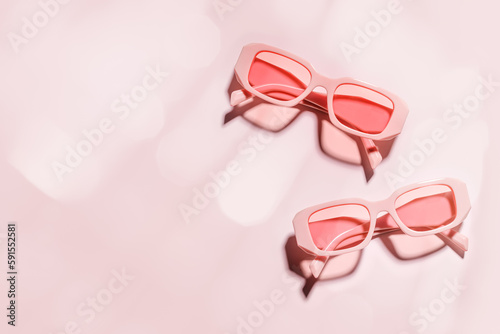 Stylish pink sunglasses with transparent rose glass on pink background, summer fashion plastic-framed glasses. Summer sale concept, pastel colored monochrome. Top view eyeglasses photo