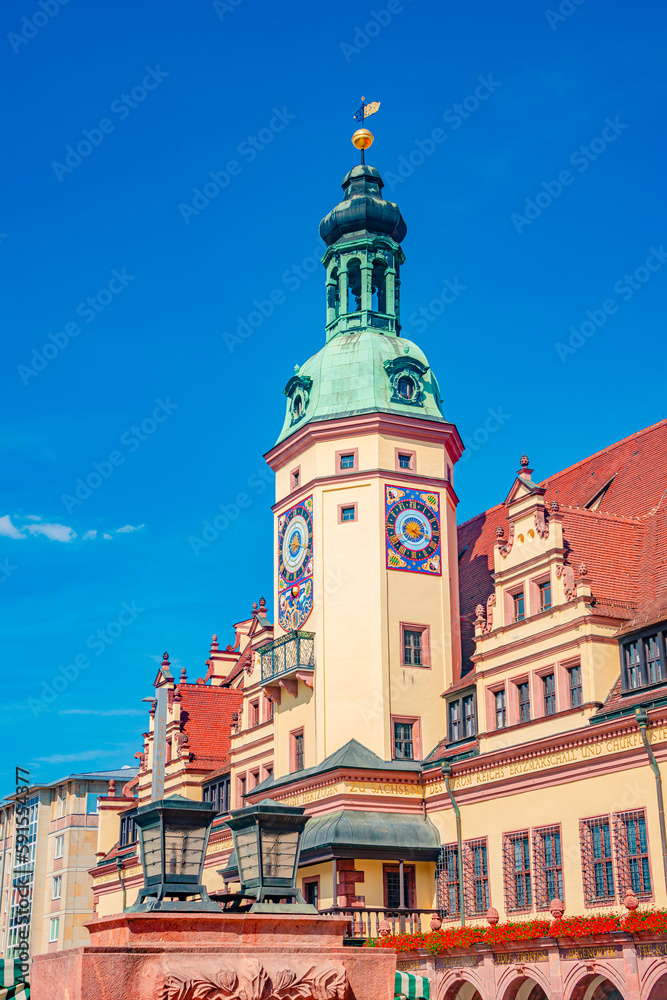 Old City Hall with clock and bell tower. Cityscape of historical downtown and shopping center in Leipzig, Germany, at summer hot sunny day.