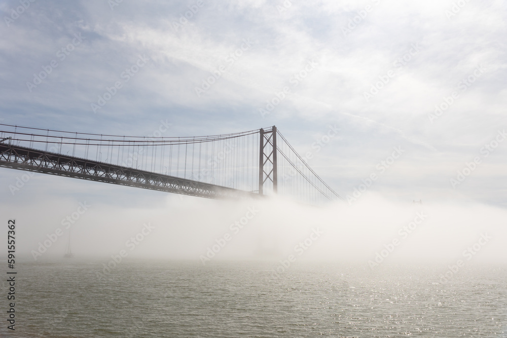 Suspension bridge shrouded in white fog over the sea