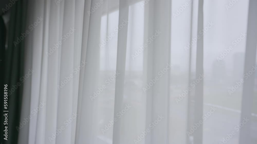 White tulle hangs on spacious window in light premise. Tulle hangs and sways on ledge along with dark curtains in room in light apartment White tulle hangs on spacious window in light premise. Tulle hangs and sways on ledge along with dark curtains in room in light apartment