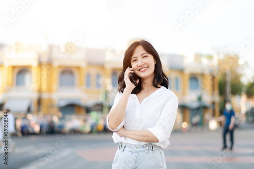 Portrait beautiful young asian woman with smart mobile phone around outdoor street view in a summer day