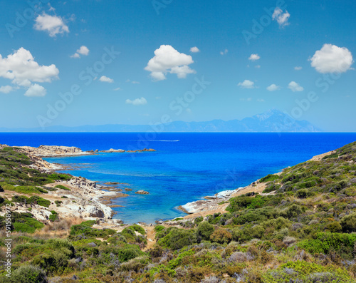 Summer stony sea coast landscape with Atthos mount view in far (Halkidiki, Sithonia, Greece).