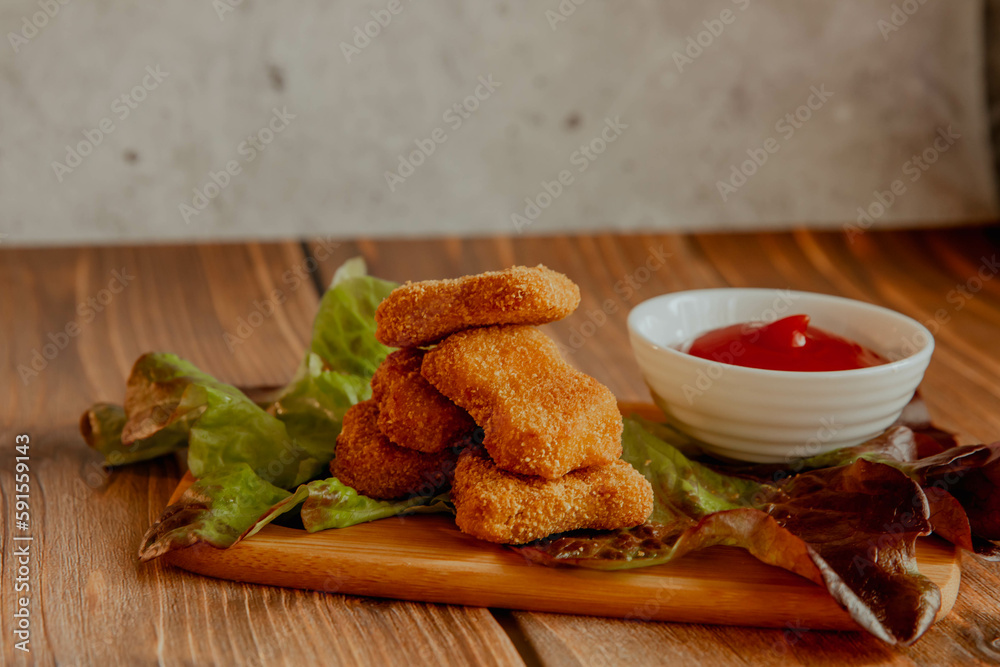 Crispy meat nuggets with tomato sauce on a wooden background