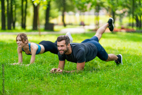Image of young smiling couple, woman training with man or bearded coach trainer, doing lath fit exercise together, looking forward ahead, outdoors. Fitness sport, healthy lifestyle concept