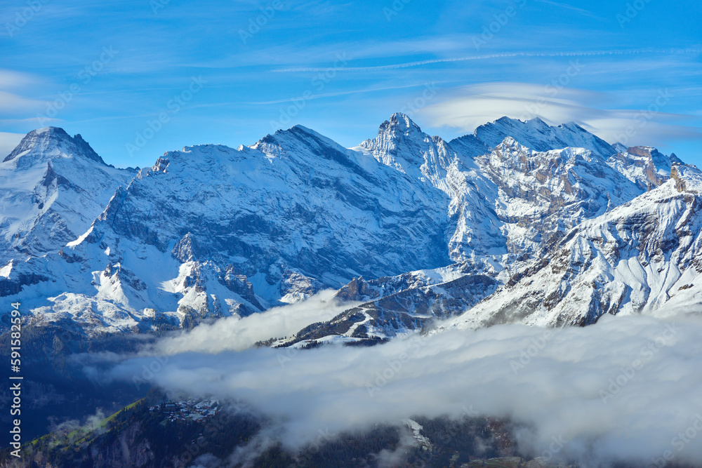 Swiss mountain snowy peaks over clouds in the valley. Bernese region in Switzerland.