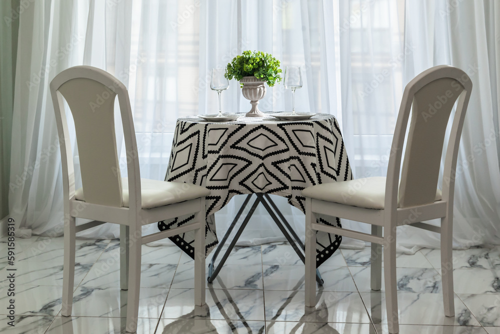 Fototapeta premium a chic bright living room with a dining table by the window and chairs serving for guests of the apartment
