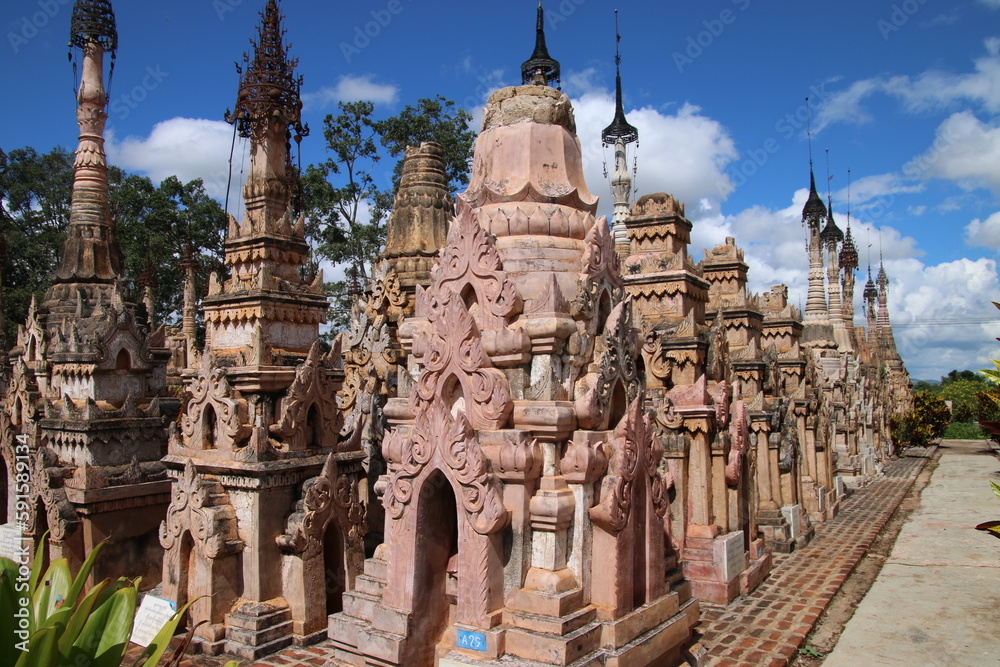 Fila de estupas o pagodas talladas en en piedra y con tonalidades rosáceas en Kakku, Birmania, Myanmar, con las puntas con campanas Fila de estupas o pagodas talladas en en piedra y con tonalidades rosáceas en Kakku, Birmania, Myanmar, con las puntas con campanas