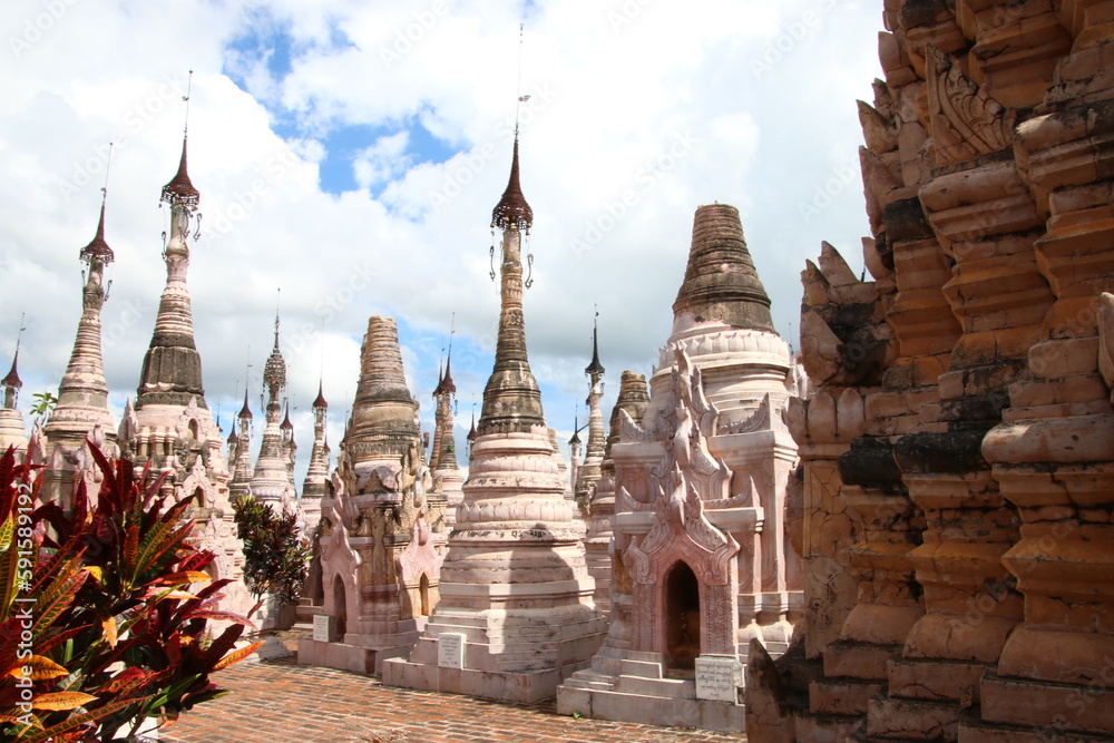 Estupas de piedra tallada en Kakku, Birmania, Myanmar,  en tonos rosáceos con un cielo cubierto de nubes blancas