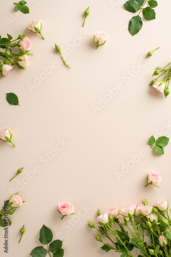 Fototapeta Naklejka Na Ścianę i Meble -  Top vertical view shot of lovely small roses on a serene beige background includes a spacious area left open for advertising, making it perfect for promotions or branding