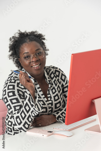 England, UK. 2023. Secretarial worker seated in a pink chair using a desktop computer photo