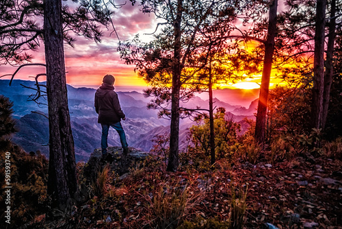man watching red sunset in amazing landscape with mountains in the background and forest in foreground, sierra madre occidental in durango mexico 