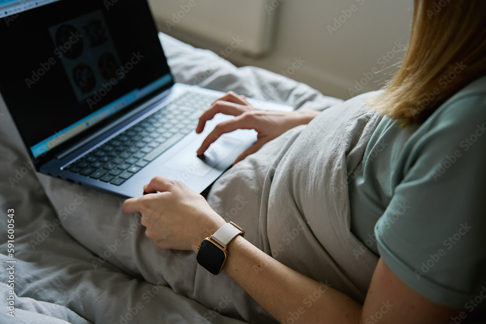 Millennial female freelancer lying in bed and using laptop. Woman work from home. Comfortable workplace. Millennial female freelancer lying in bed and using laptop. Woman work from home. Comfortable workplace.
