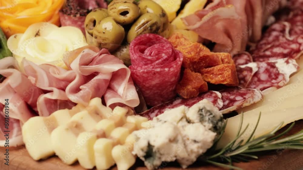 Charcuterie and cheese platter rotates smoothly around its axis. Appetizers boards with assorted cheese, salami, ham, grape and nuts. Video is looped
