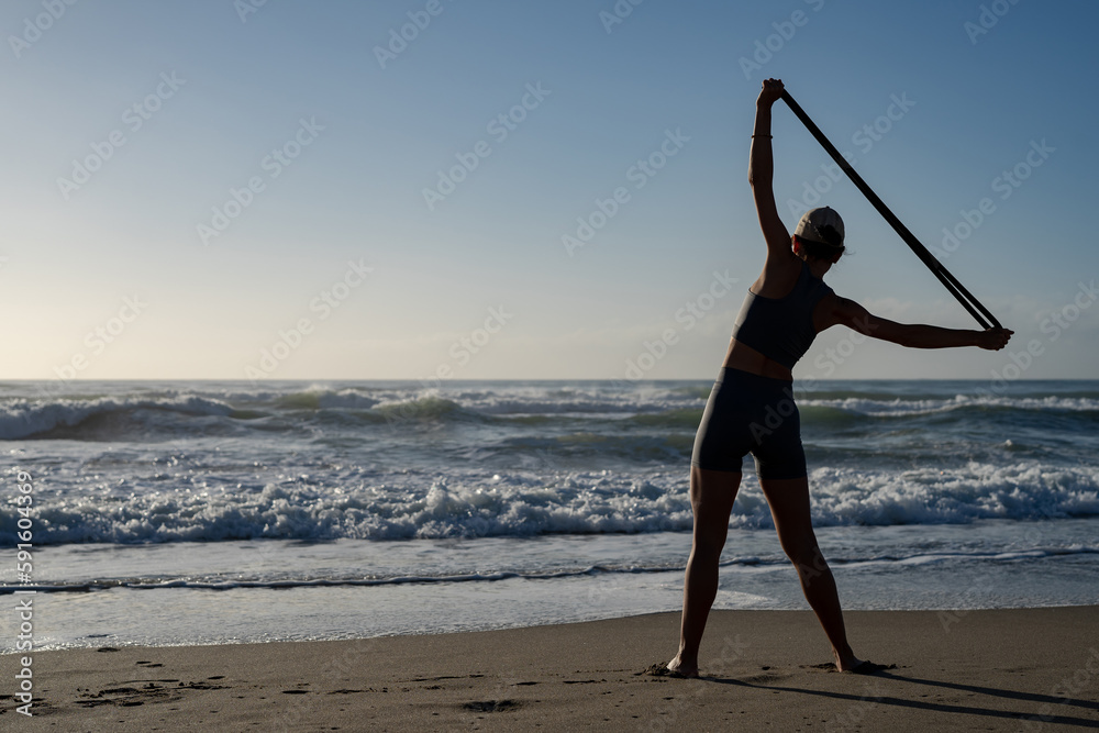 beautiful young girl goes in for sports on the seashore does different exercises