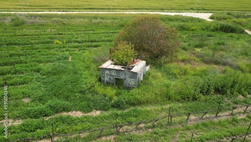 aerial view of lonley old shack in the middle of green feilds
