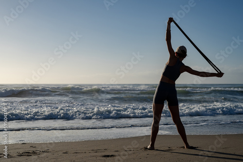 beautiful young girl goes in for sports on the seashore does different exercises