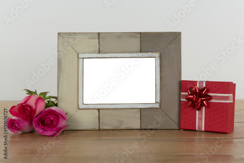 Photo frame, rose flower and gift boxes on a table