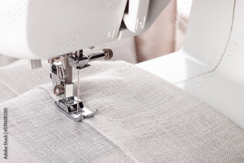 Modern sewing machine presser foot with linen fabric and thread, closeup. Sewing process clothes, curtains, upholstery. Business, hobby, handmade, zero waste, recycling, repair concept