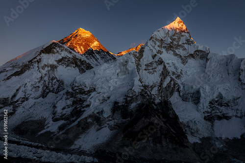 Late orange sunset on summits of Mount Everest and Nuptse, photo taken from Kala patthar. Last rays of sunlight hitting the peaks with dark sky in the background