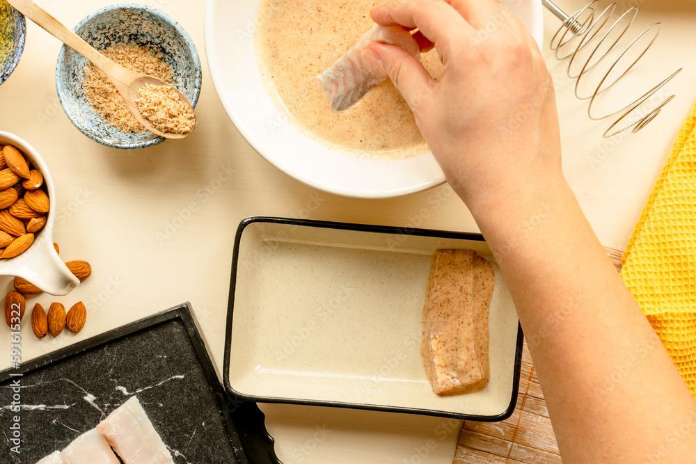 making fish and chips, woman's hand making batter coated white fish for ...