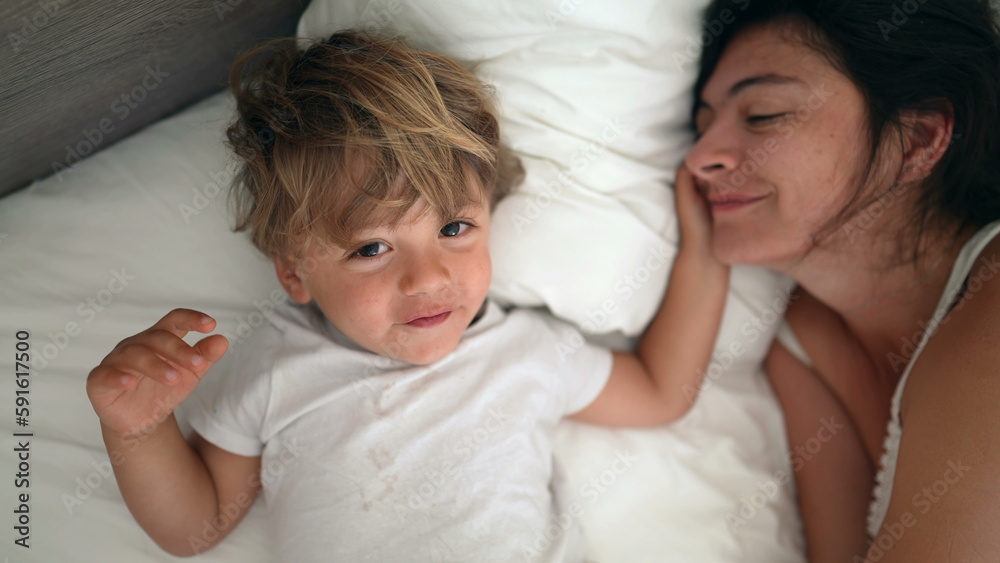 Closeup little boy son laying in bed with mom during weekend. Happiness family lifestyle concept Closeup little boy son laying in bed with mom during weekend. Happiness family lifestyle concept