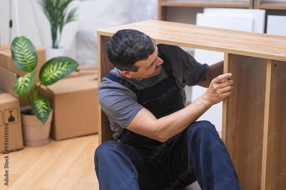Skilled Craftsman Assembling and Repairing Furniture in blue uniform for a Beautifully Furnished Home. Handyman service professional Skilled Craftsman Assembling and Repairing Furniture in blue uniform for a Beautifully Furnished Home. Handyman service professional